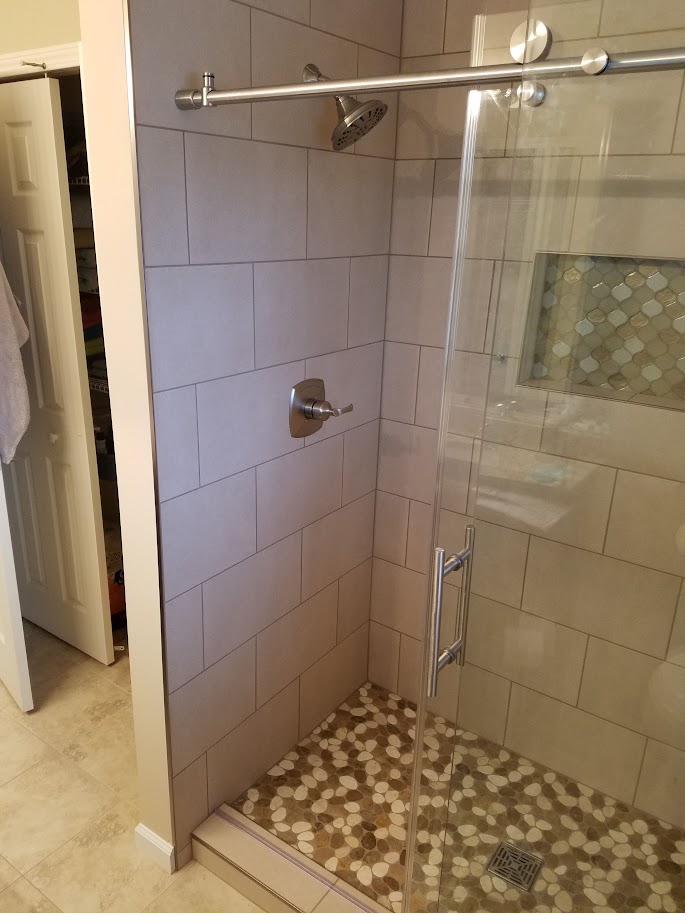 Finished shower with gray subway tile and pebble floor