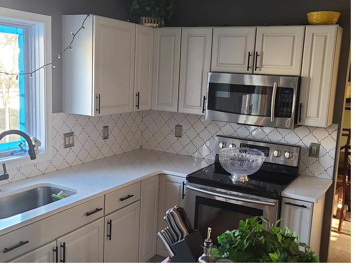 Finished kitchen with arabesque tile backsplash and quartz counters
