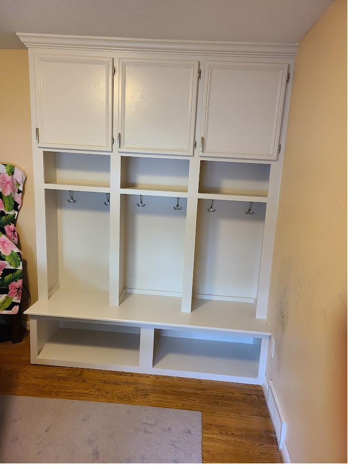 Painted built-in mudroom cabinet with open cubbies and hooks